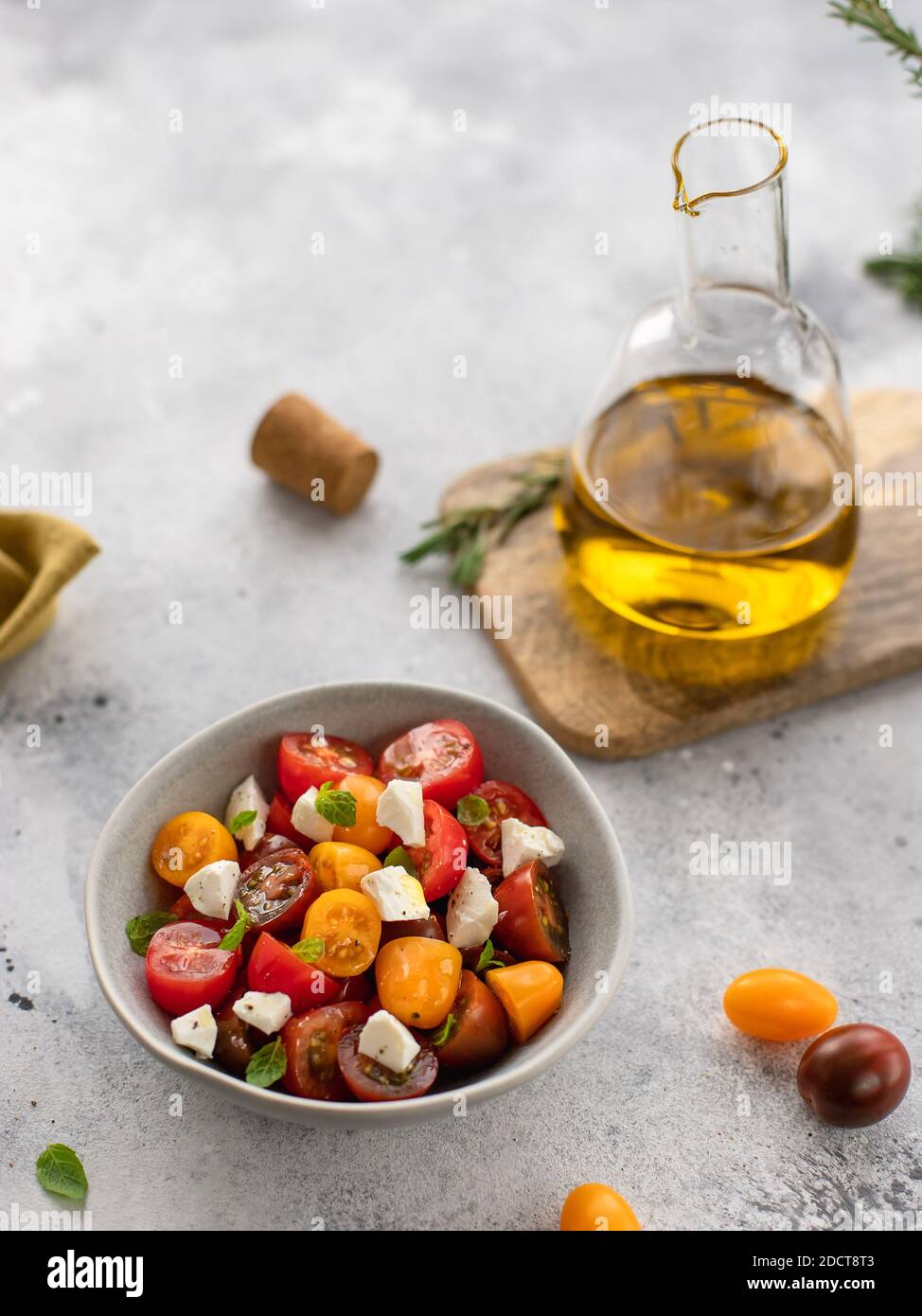 salad with fresh tomatoes, feta cheese, basil, olive oil. vegitarian healthy concept. gray background, copy space, vertical image Stock Photo