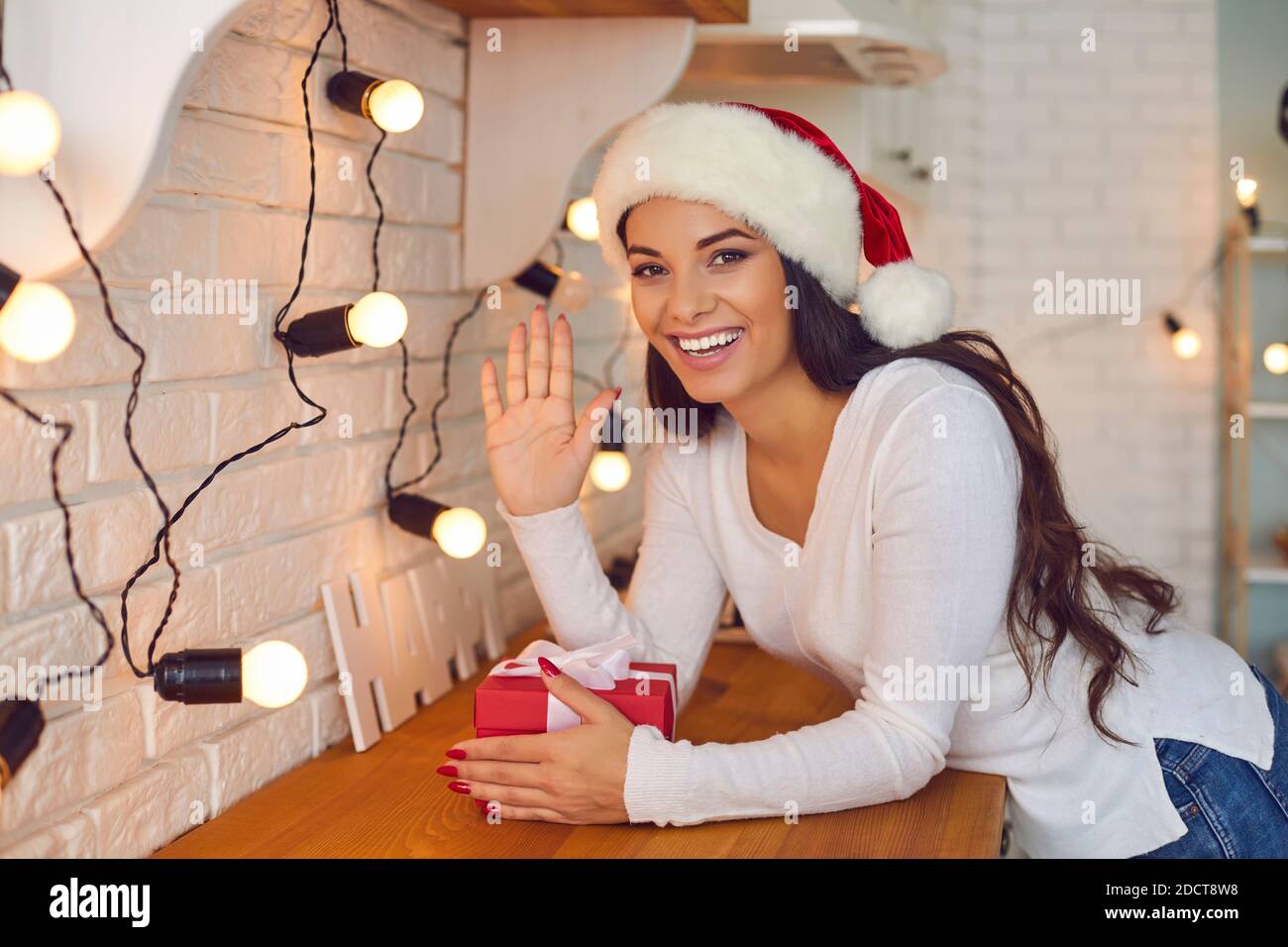 Friendly woman waves his hand in front of the webcam greeting his friends on a video call. Stock Photo