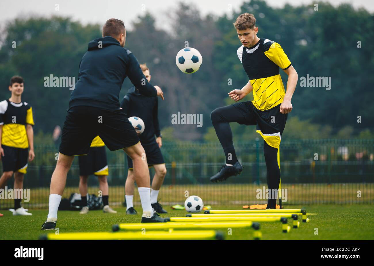 Youth Footballers on Training Session With Young Coach. Soccer Camp for Teenagers. Boy Kicking Ball on Practice Unit. Caucasian Boys Improving Soccer Stock Photo