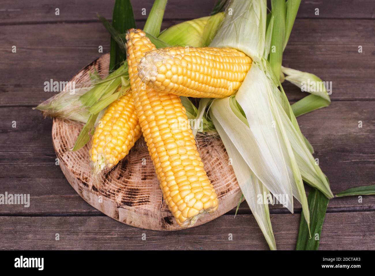 Natural cob of corn in husks on a wooden background. The concept of ...