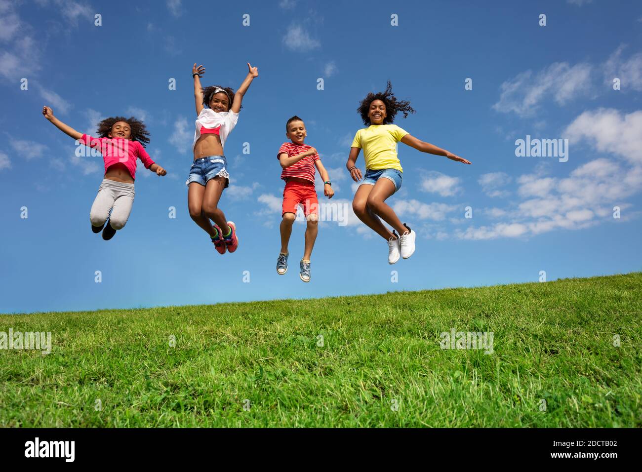 Group of kids jump high over blue sky and clouds, Stock image