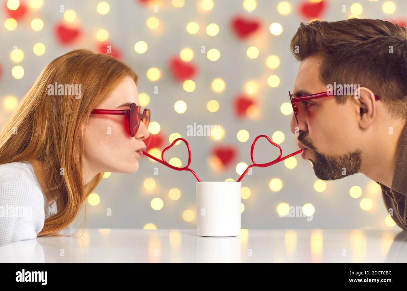 https://c8.alamy.com/comp/2DCTCBC/funny-young-couple-sipping-drink-through-heart-shaped-straws-on-st-valentines-day-date-2DCTCBC.jpg