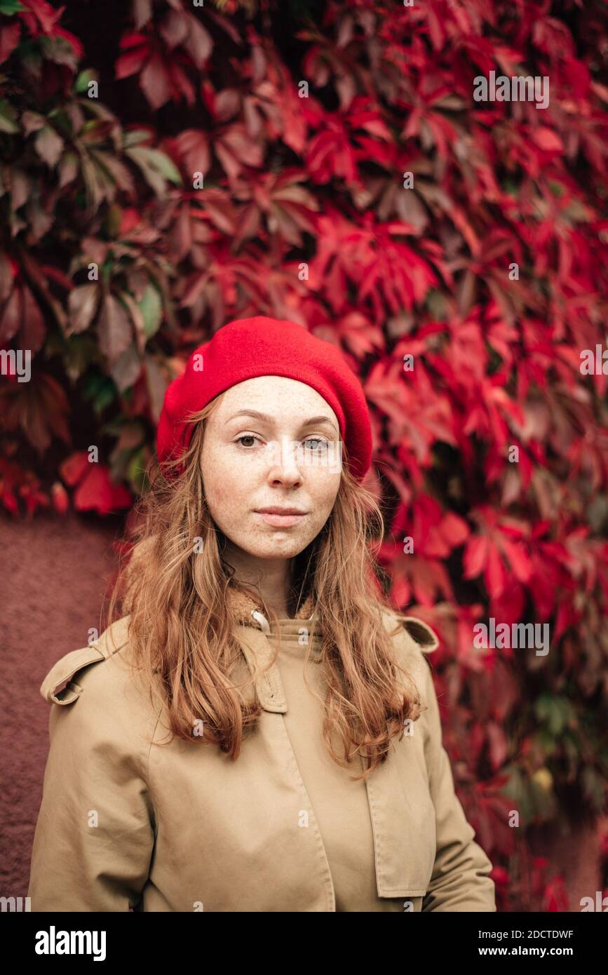 red-haired girl in a red beret and trench coat stands against the ...