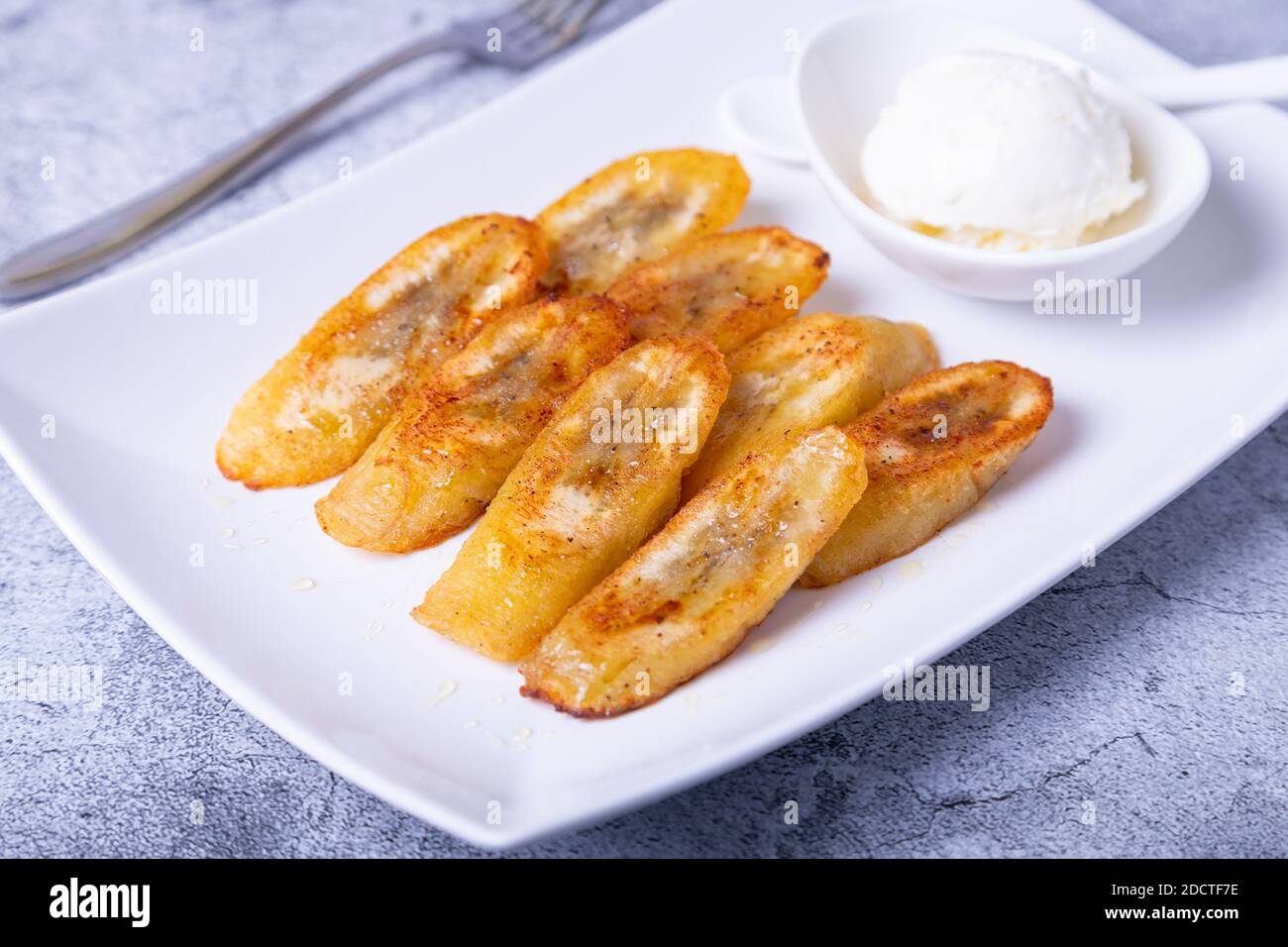 Fried bananas with honey, cinnamon and ice cream. Closeup Stock Photo