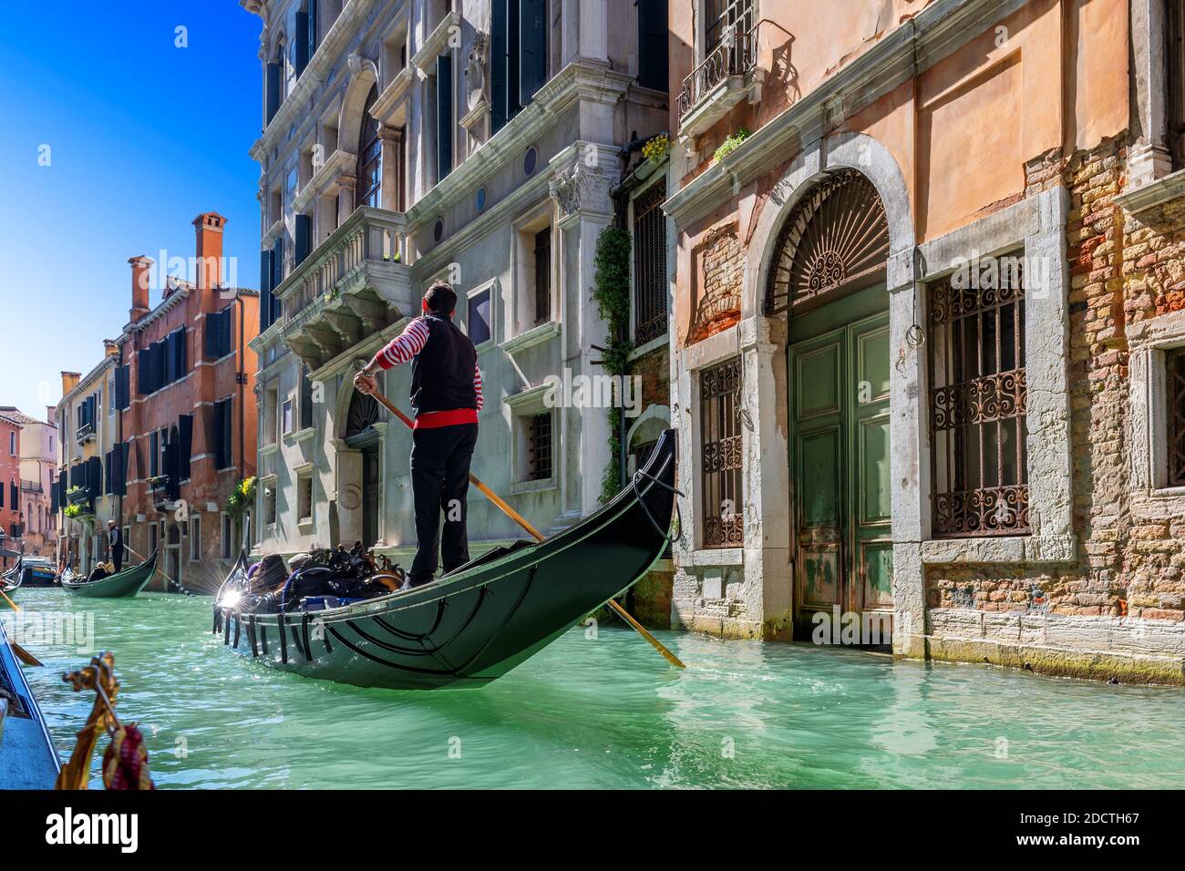 A Venetian gondolier rules a gondola Through the waters of the Venice canal, Venice, Italy Stock Photo