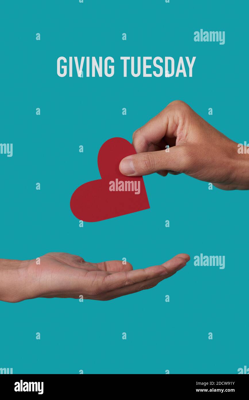a person giving a red heart to another person and the text giving tuesday on a blue background Stock Photo