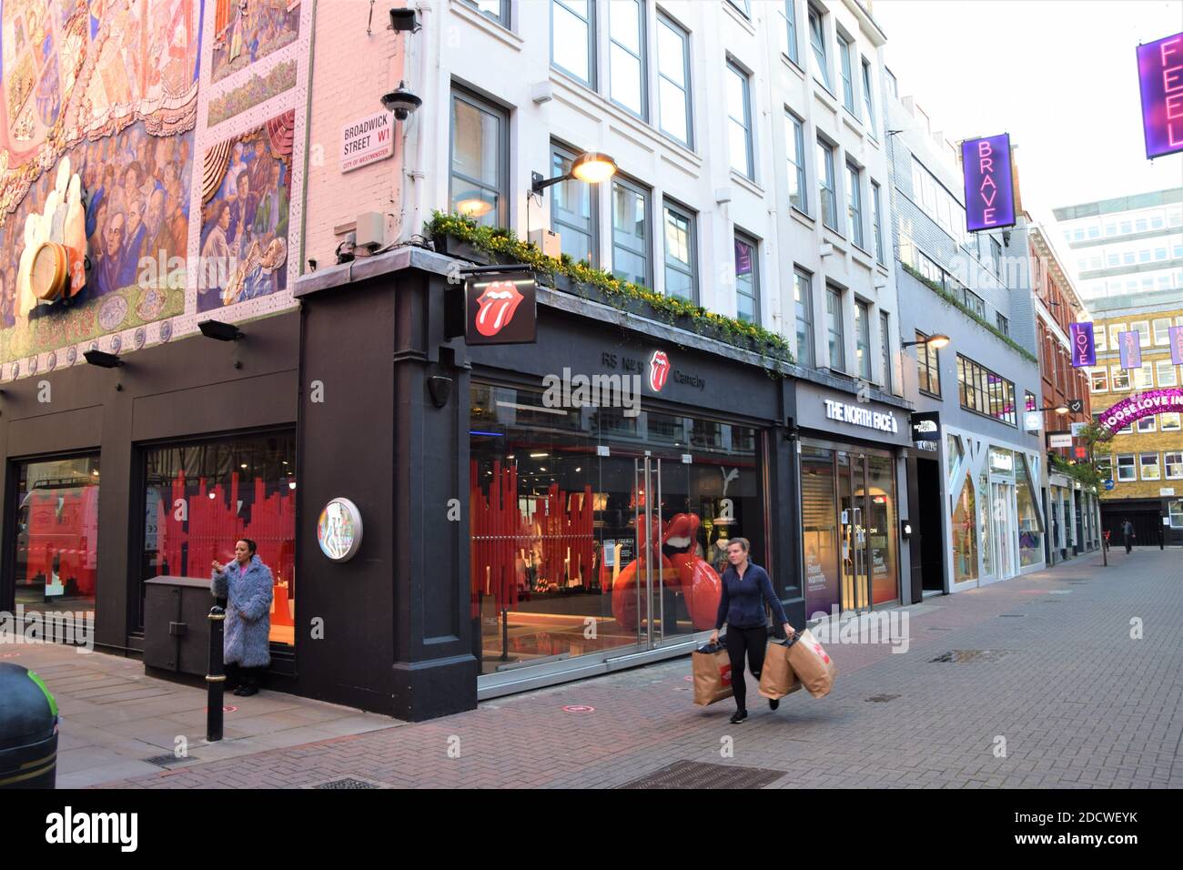 A woman carrying shopping bags walks past the Rolling Stones shop on  Carnaby Street, London Stock Photo - Alamy
