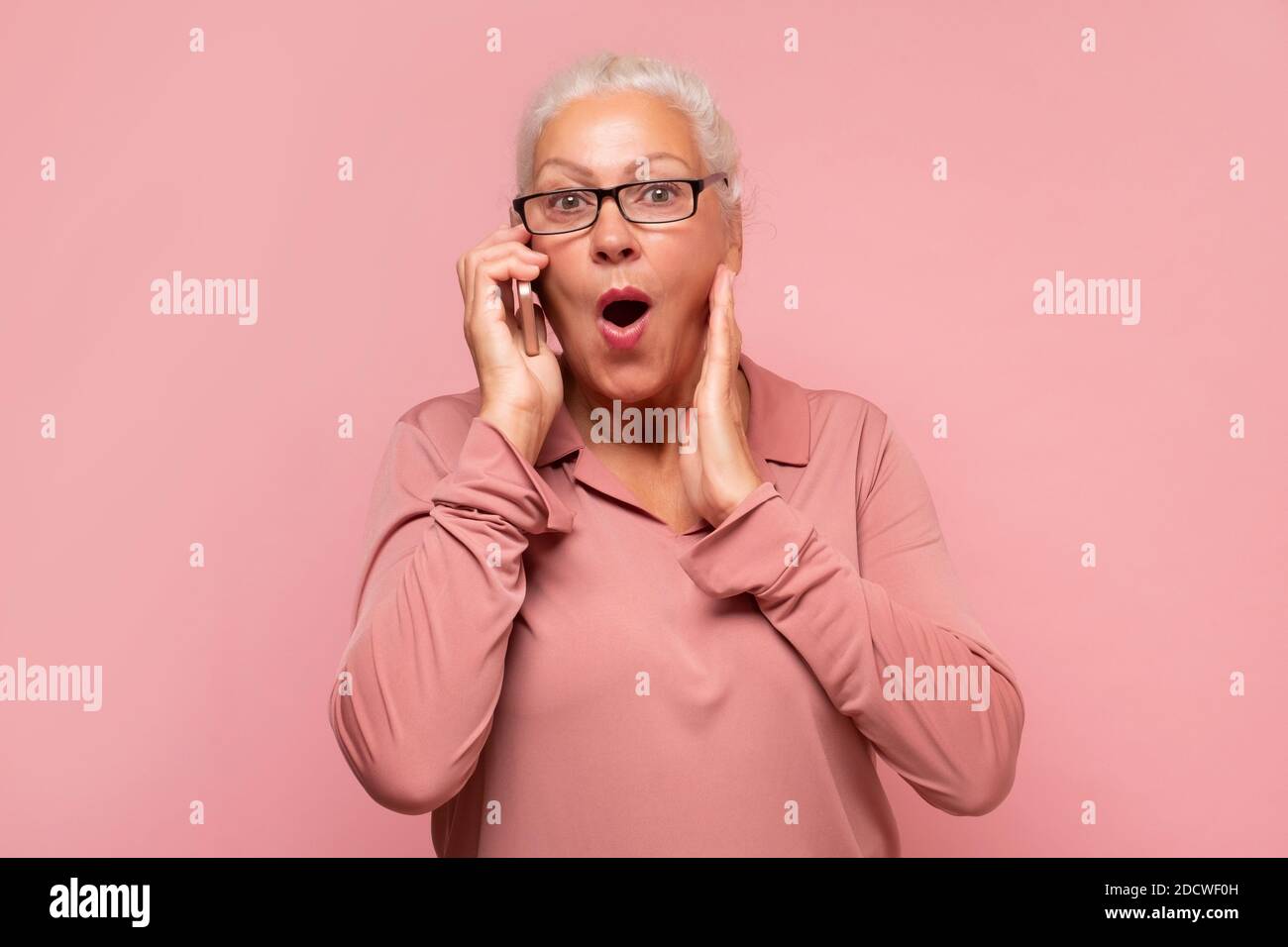 Old lady talking on mobile phone, telling latest gossip to her friend. Stock Photo