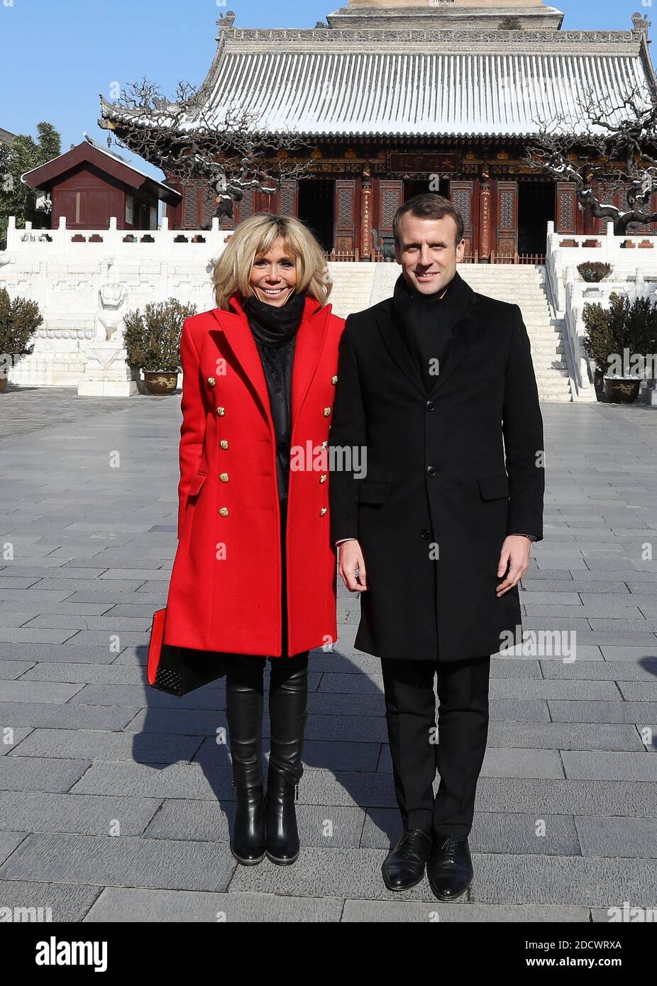 French President Emmanuel Macron and his wife Brigitte Macron listen to a  priest during a visit at the Big Wild Goose Pagoda in the northern Chinese  city of Xian, China on January