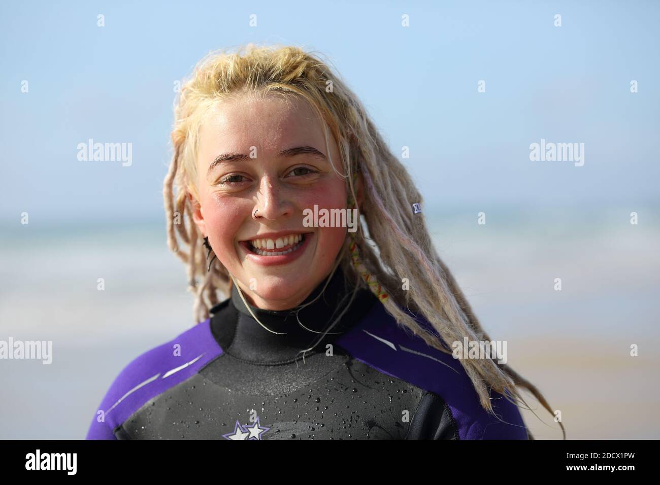 Portrait of happy female Surfer with dreadlocks at Fistral Beach in Newquay , Cornwall, England Stock Photo