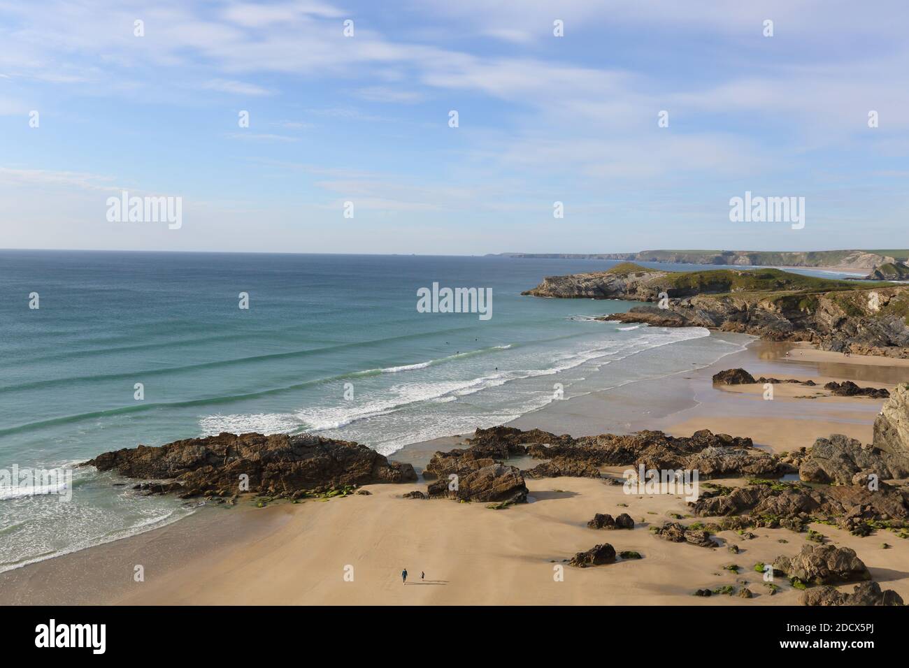 A panoramic view of a two people walking on the beach looking out over Watergate Bay in North Cornwall , South West Coast path Stock Photo