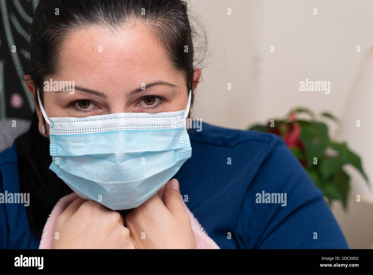 Close-up of flu or covid19 virus infection sick feeling unwell adult female model wearing disposable surgical or medical protective mask as influenza Stock Photo