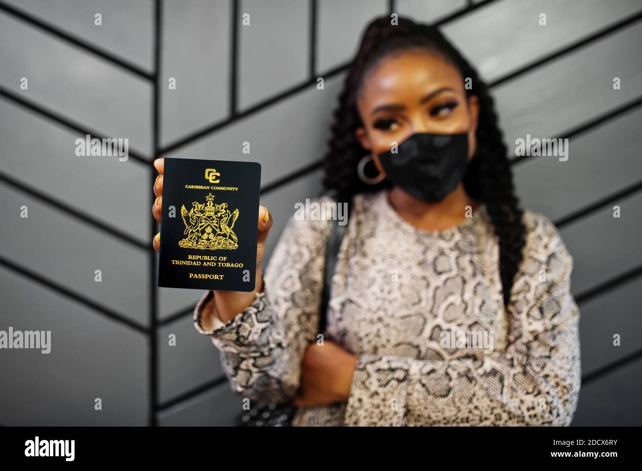 African american woman wearing black face mask show Trinidad and Tobago passport in hand. Coronavirus in America country, border closure and quarantin Stock Photo