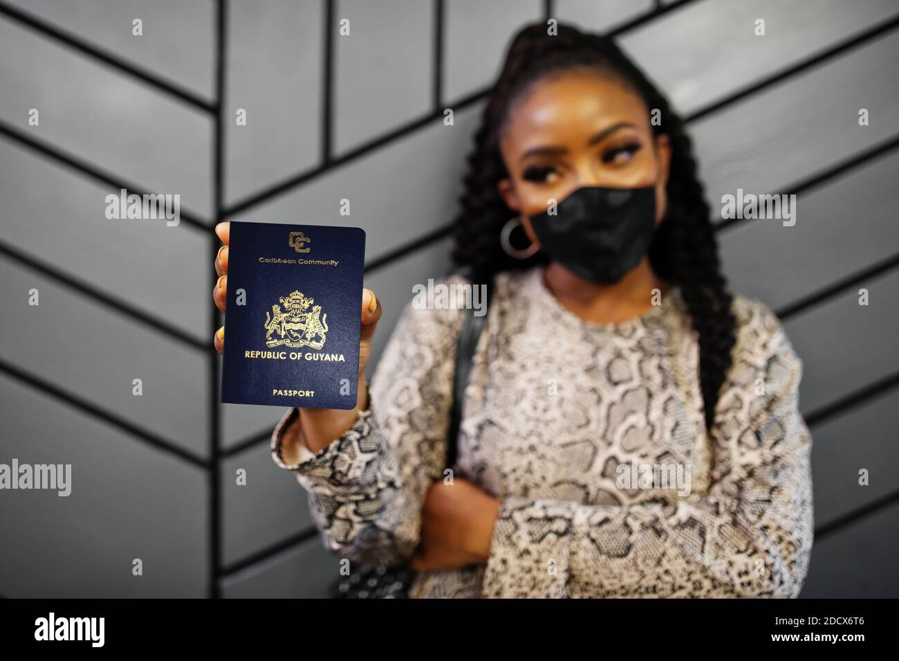 African american woman wearing black face mask show Guyana passport in hand. Coronavirus in America country, border closure and quarantine, virus outb Stock Photo