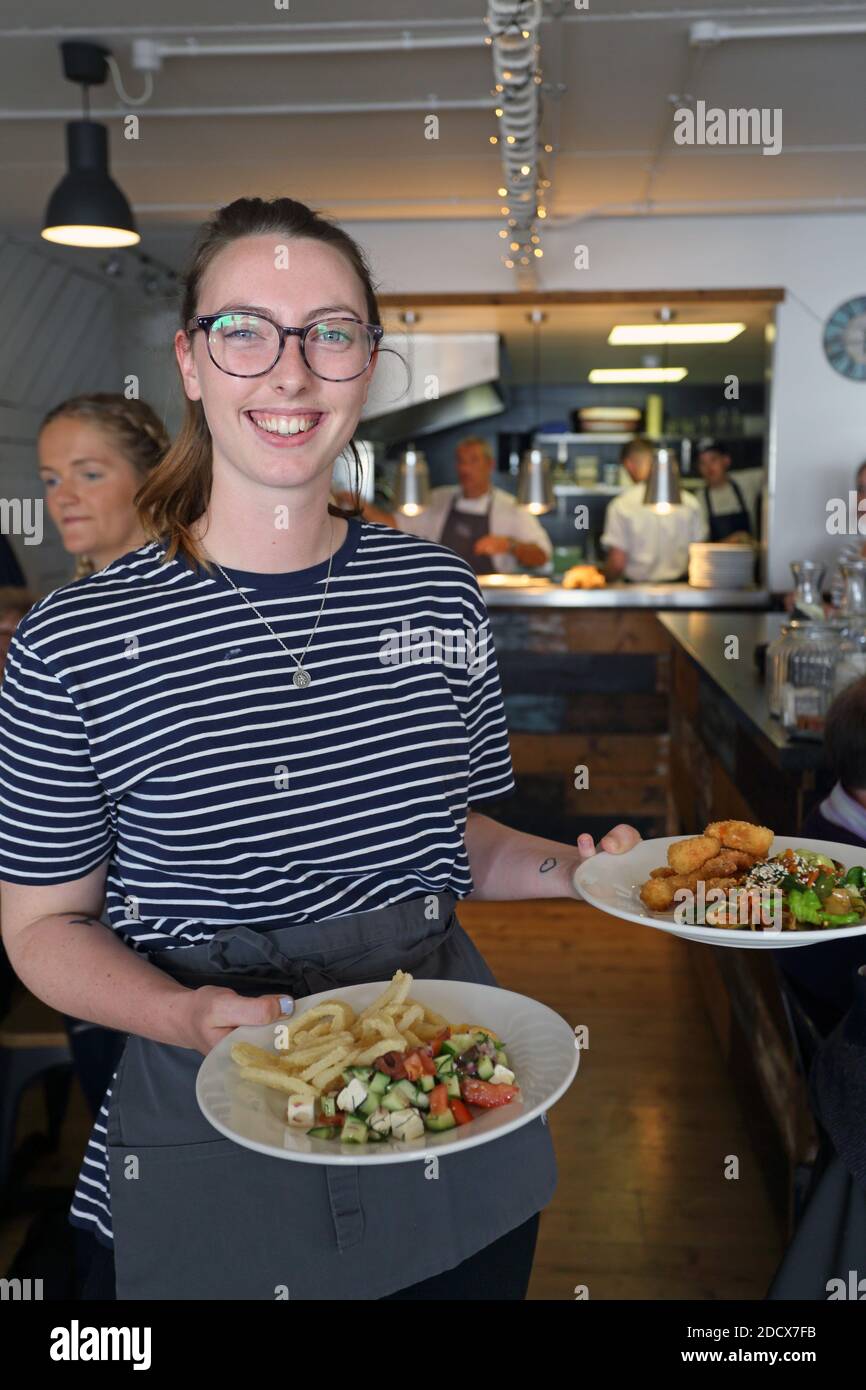 GREAT BRITAIN /Cornwall/ Newquay /Female restaurant staff serve food at The Fish House at Fistral in Newquay in Cornwall. Stock Photo
