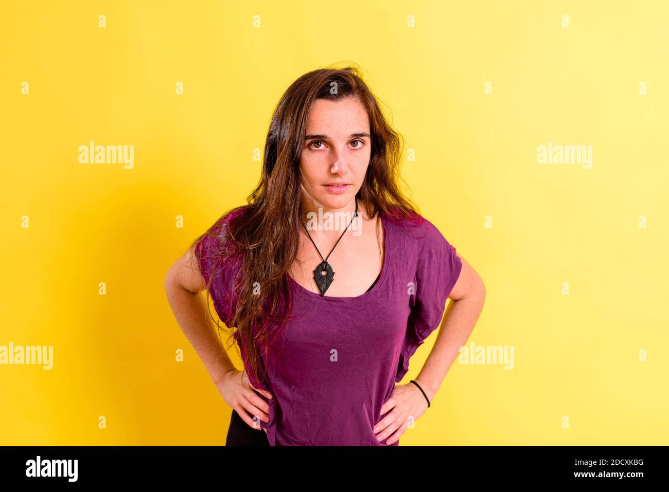 portrait of pretty 25 years old real girl without makeup posing looking at camera isolated on yellow studio background. Stock Photo