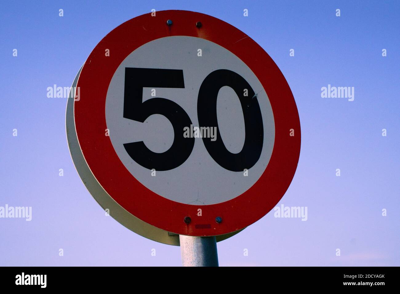 Round red and white 50 speed limit sign with blue sky in the background Stock Photo