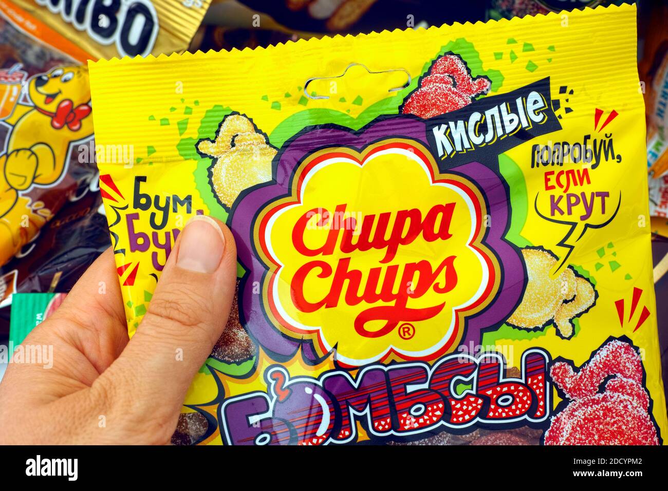 Tambov, Russian Federation - October 30, 2020 Woman hand taking pack of Chupa Chups gummy candy. A lot of sweet snacks on background. Stock Photo
