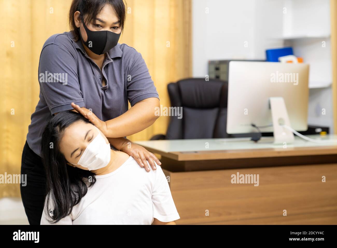 Quarantine asian woman do massage at home with face mask while city lockdown for social distance due to coronavirus pandemic. Massage is one of servic Stock Photo
