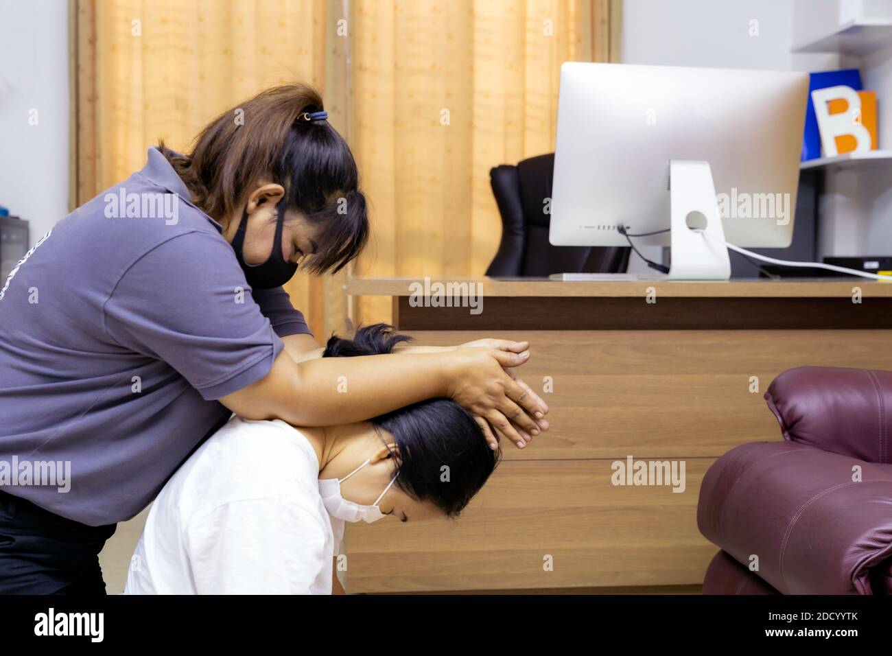 Quarantine asian woman do massage at home with face mask while city lockdown for social distance due to coronavirus pandemic. Massage is one of servic Stock Photo