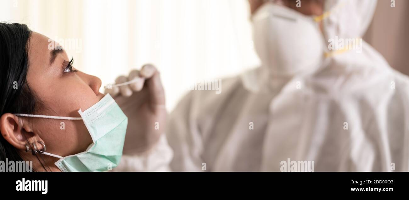 Panorama Medical staff with PPE suit test coronavirus covid-19 to asian woman by nose swab at hosputal. COVID-19 testing health care concept. Stock Photo