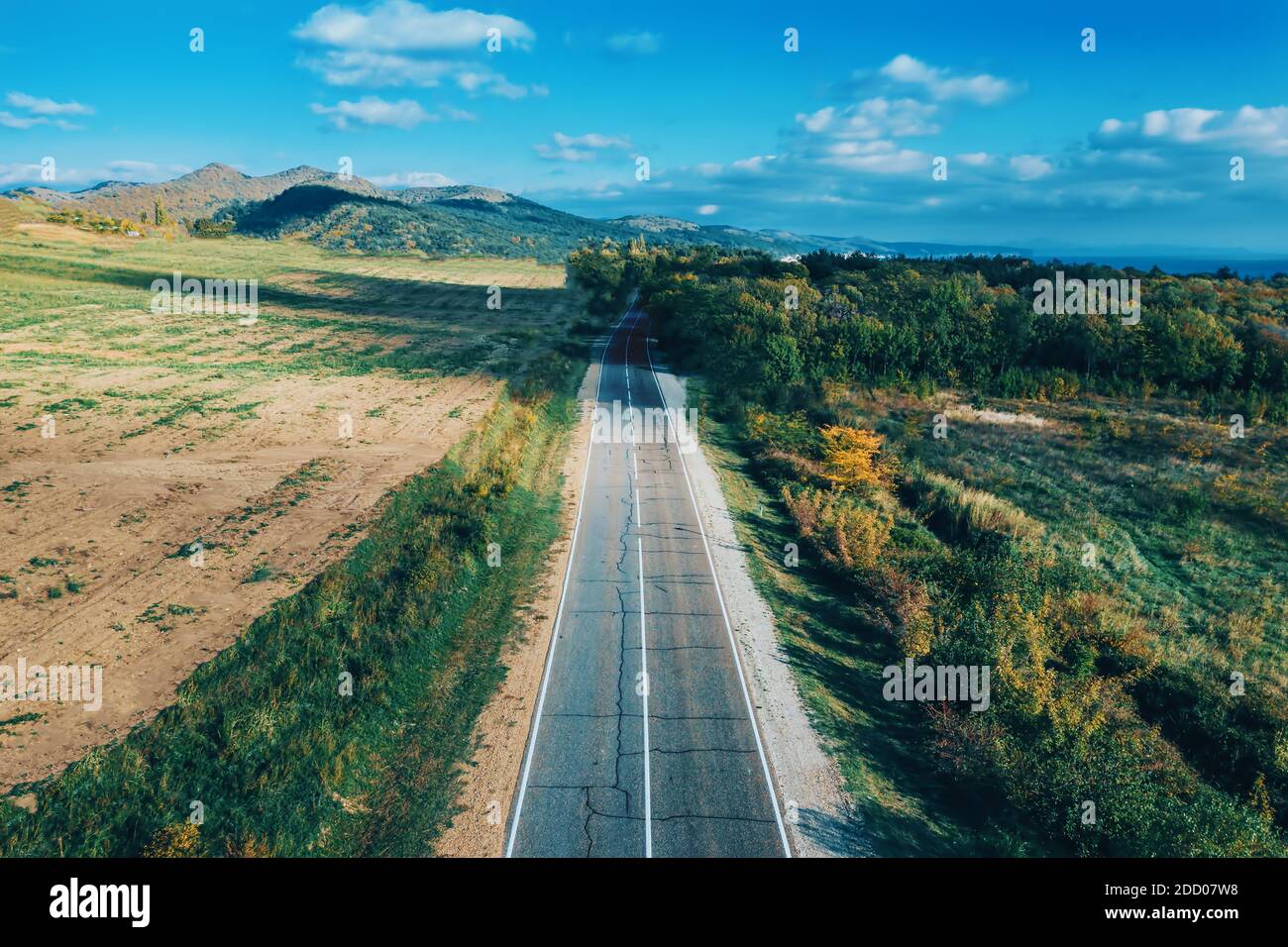 Empty asphalt road or route, or way in mountain countryside among green meadows and forest as idea of freedom and travel. Stock Photo