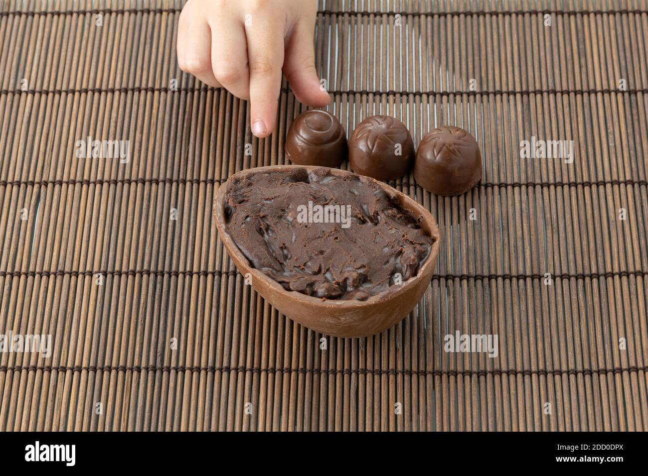 Child picking up one of the candies next to the chocolate Easter egg