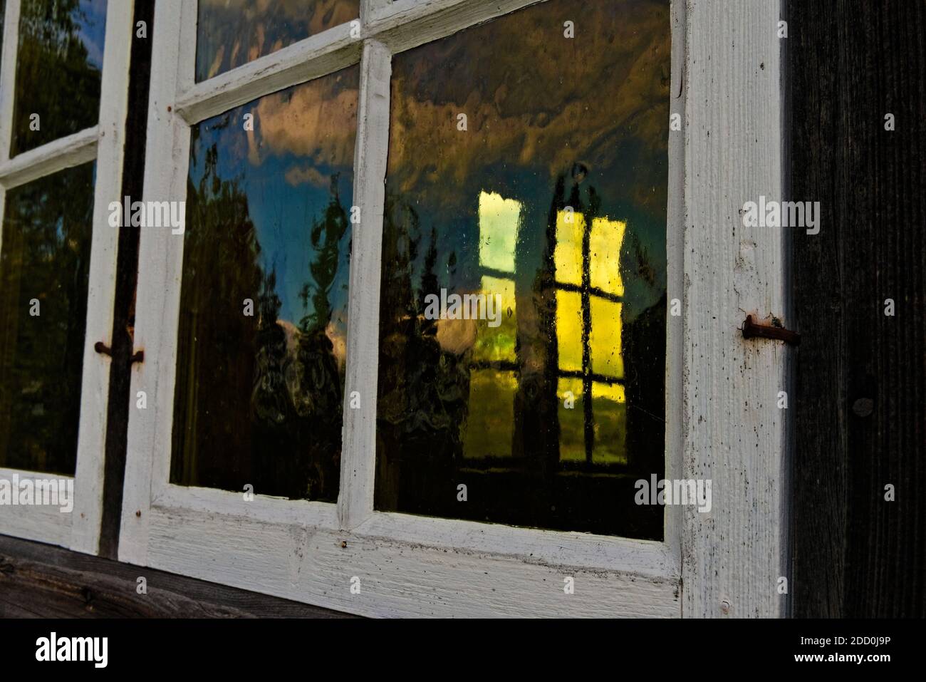 Close-up and angle on an old window in a white frame with yellow tinted glass. Stock Photo