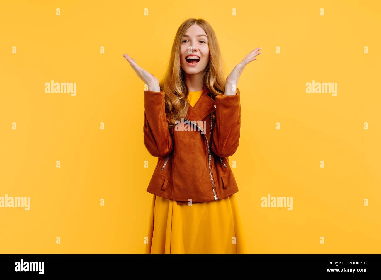 Excited, shocked, screaming, happy, beautiful girl, in a bright yellow dress and autumn jacket, is happy standing on an yellow background. The concept Stock Photo