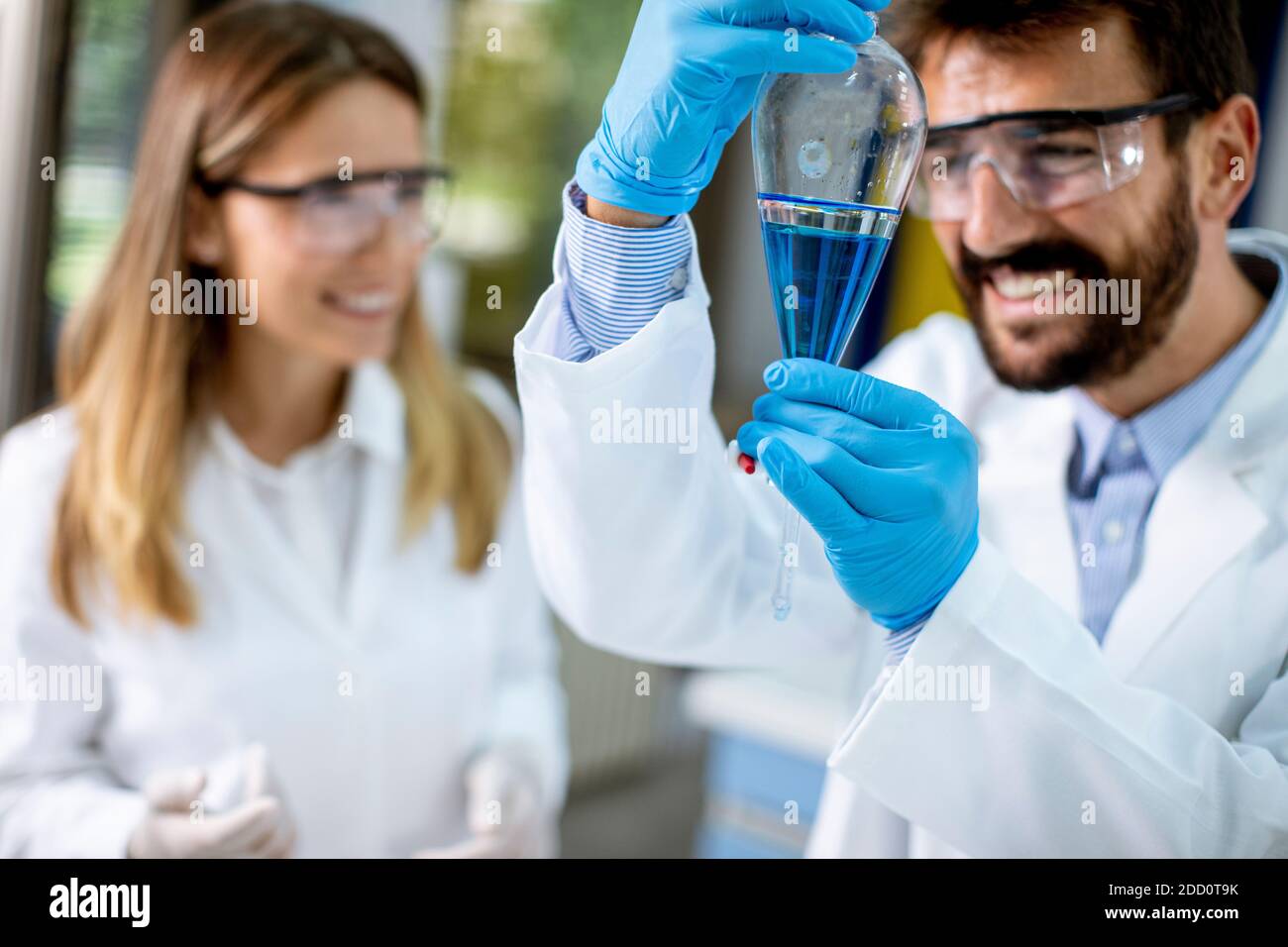 Researcher working with blue liquid at separatory funnel in the