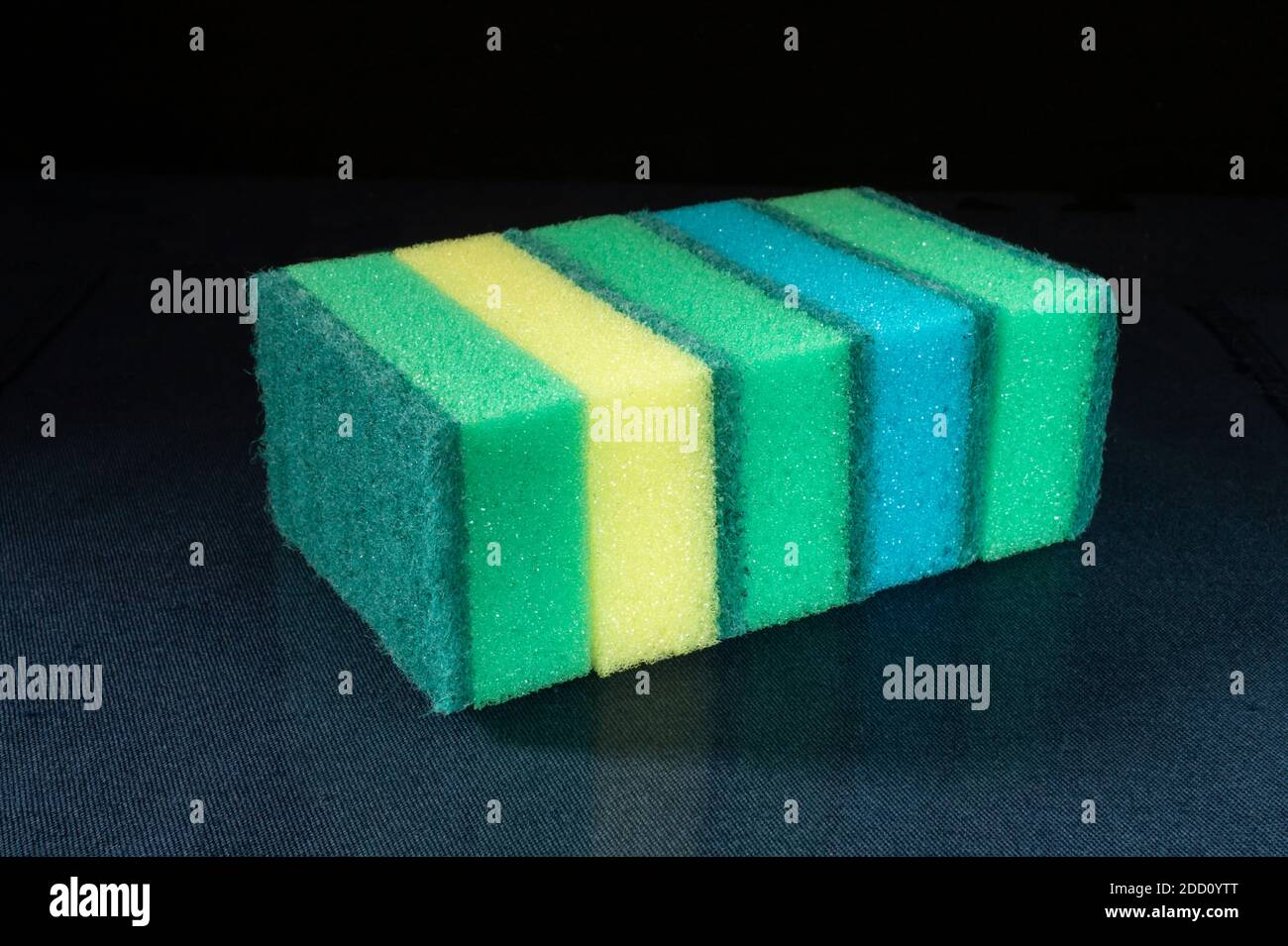 The Sponge for dishwashing on glass table on black background.The New facility hygiene. Porous and soft material Stock Photo