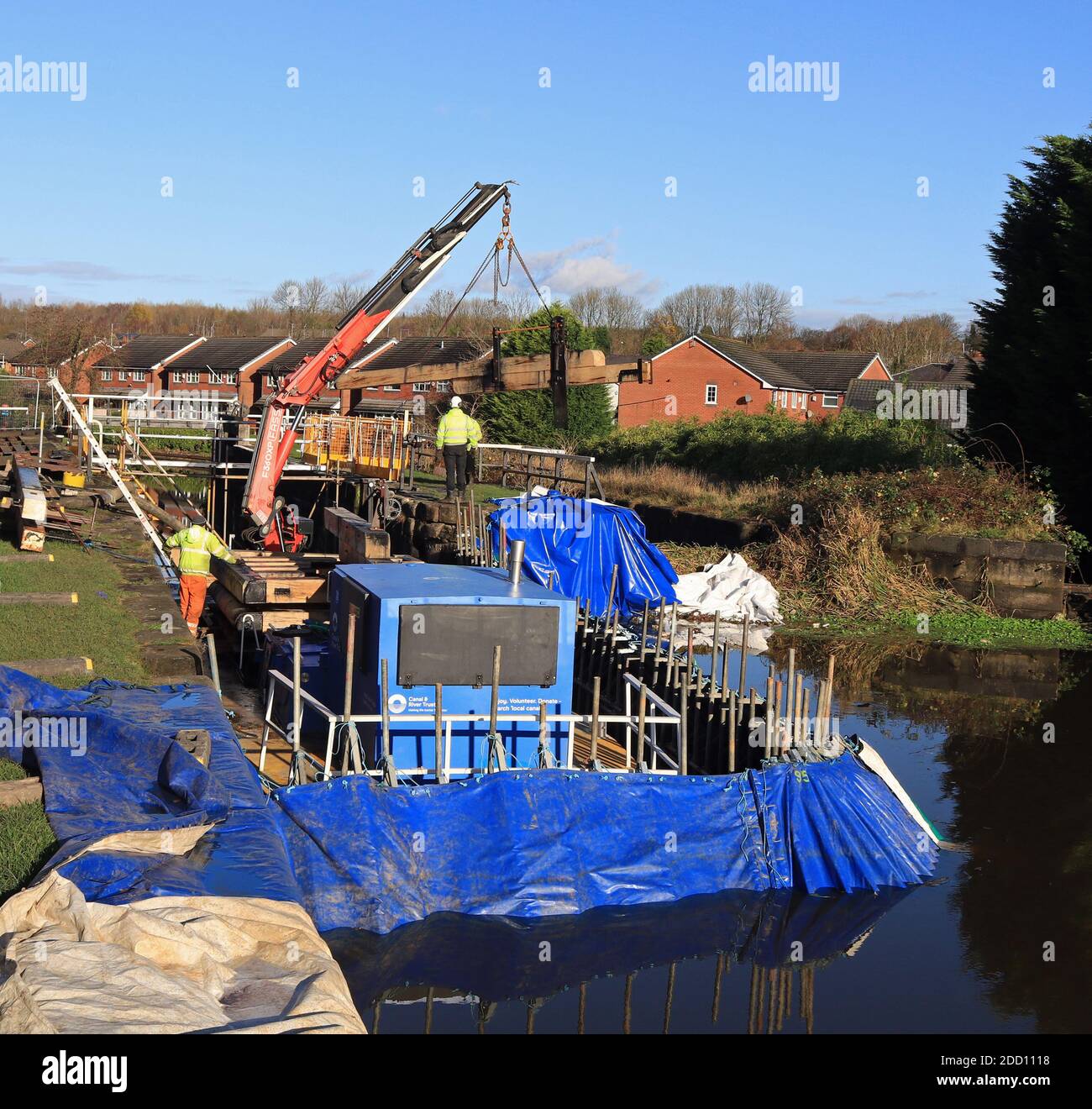 A new wooden lock beam is lifted of a work boat and is placed on the lock landing as part of the fitting new head gates at Ell Meadow lock near Wigan. Stock Photo