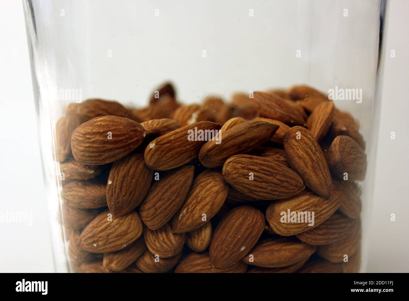 Delicious raw almonds stored in a vintage glass jar photo isolated on white background Stock