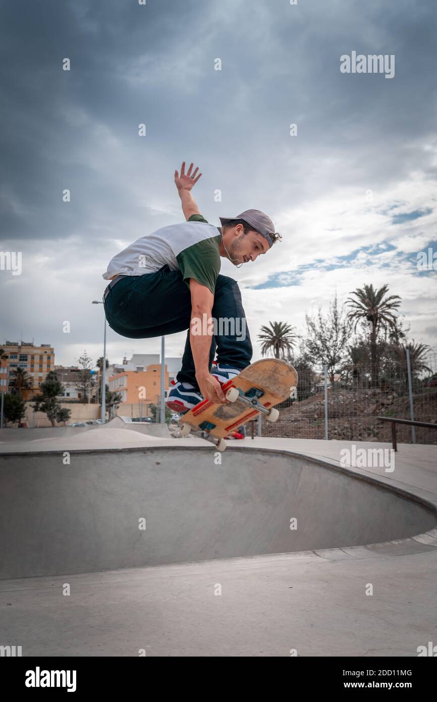 young man does a trick called melon grab in a skate park. vertical