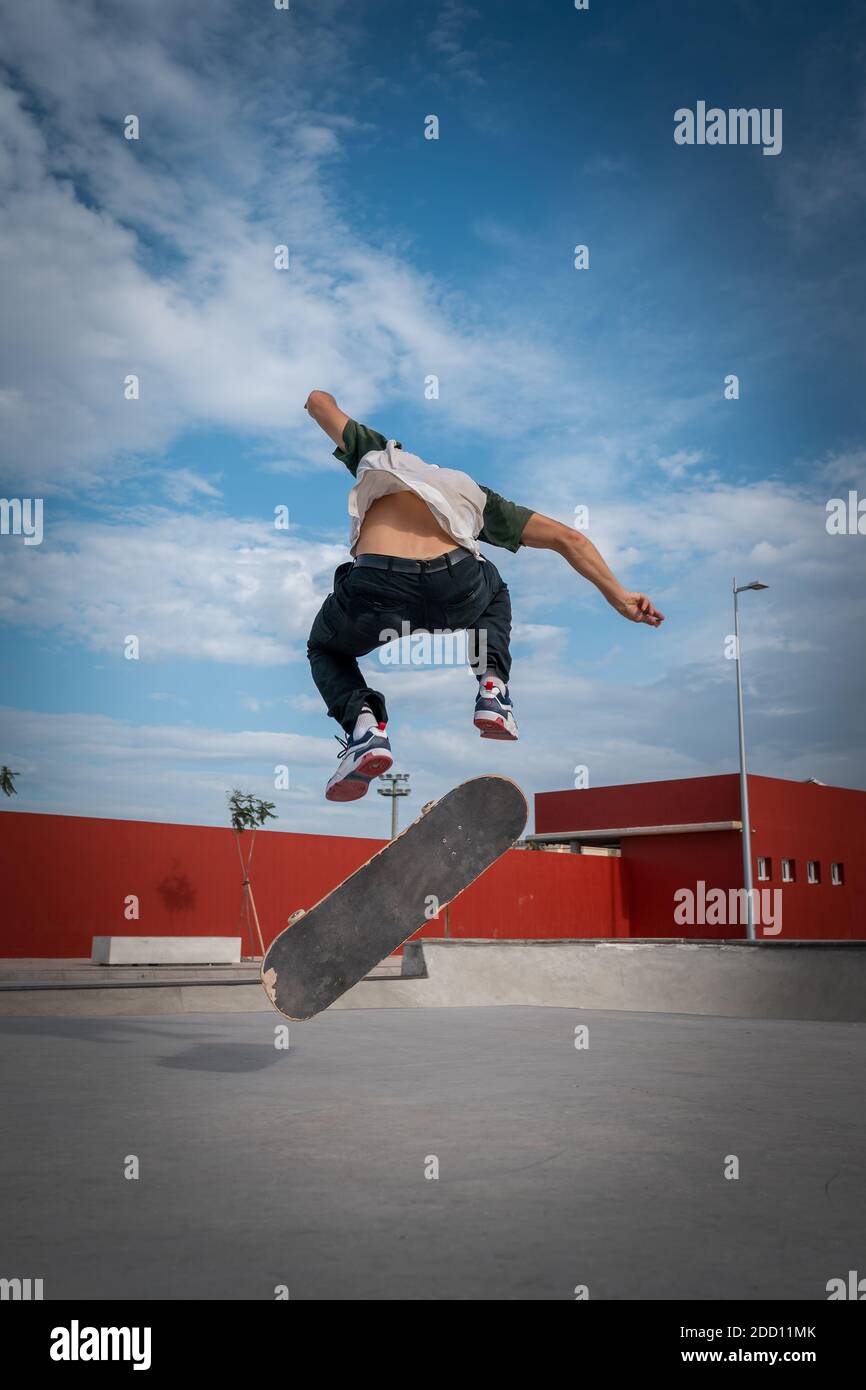 young man does a trick called heelflip in a skate park. movement 1.  vertical composition Stock Photo - Alamy