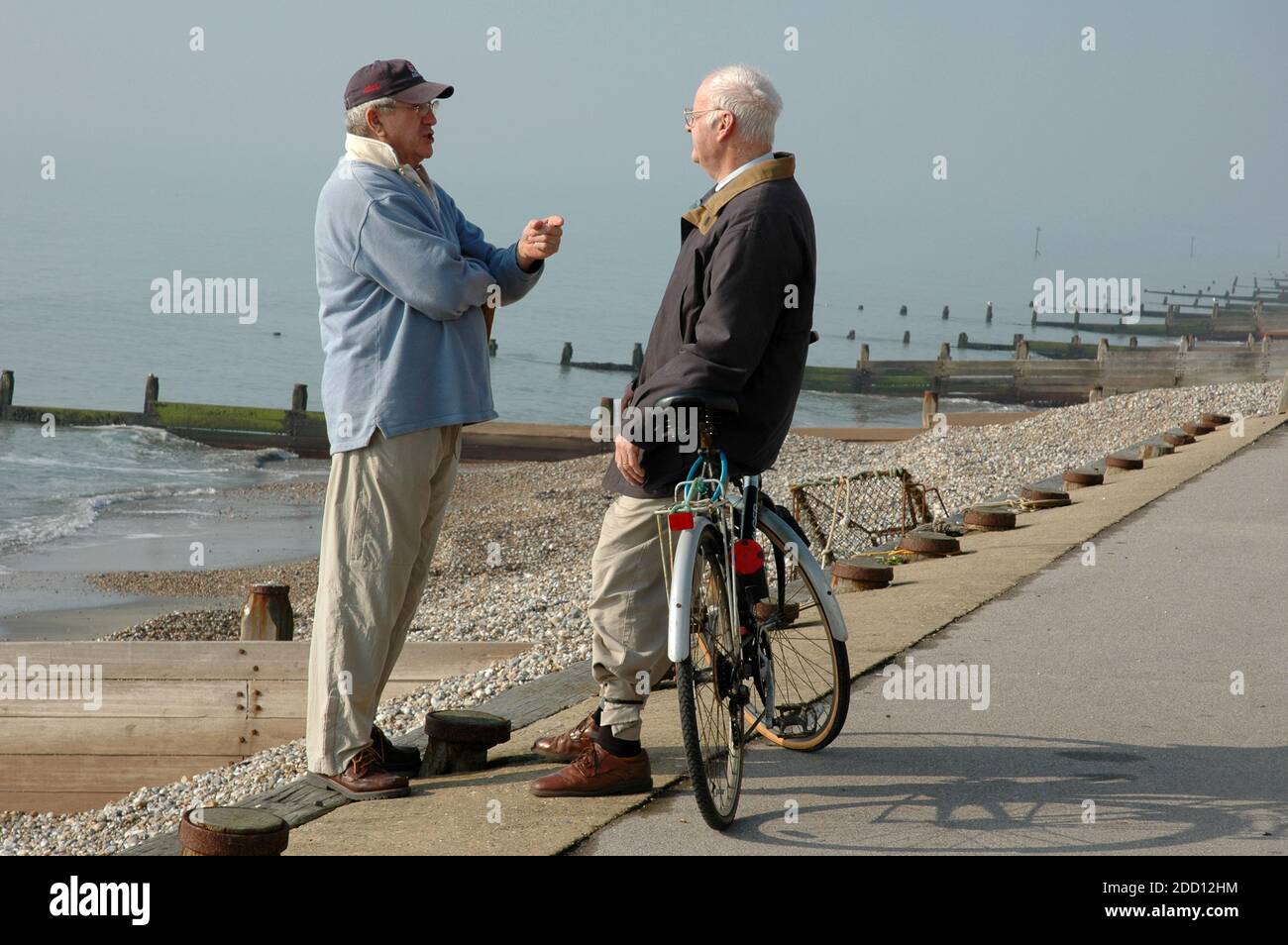 Two men, middle aged to elderly, standing on coast path having a discussion. East Wittering, West Sussex. Stock Photo