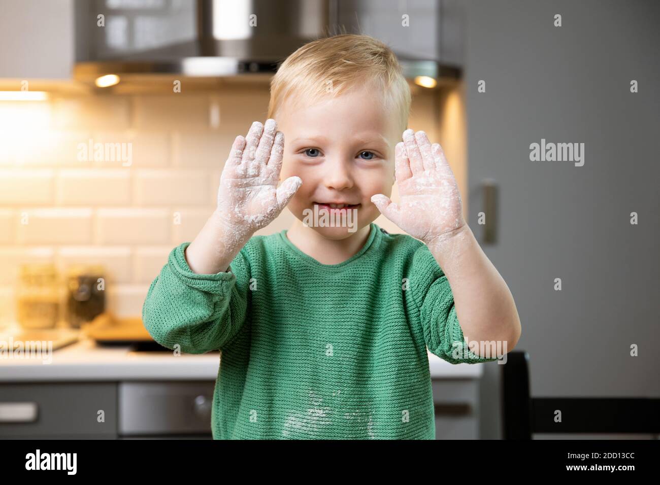Young boy child playing with flour in a cozy kitchen at home. Happy family and hobby concept. Stock Photo