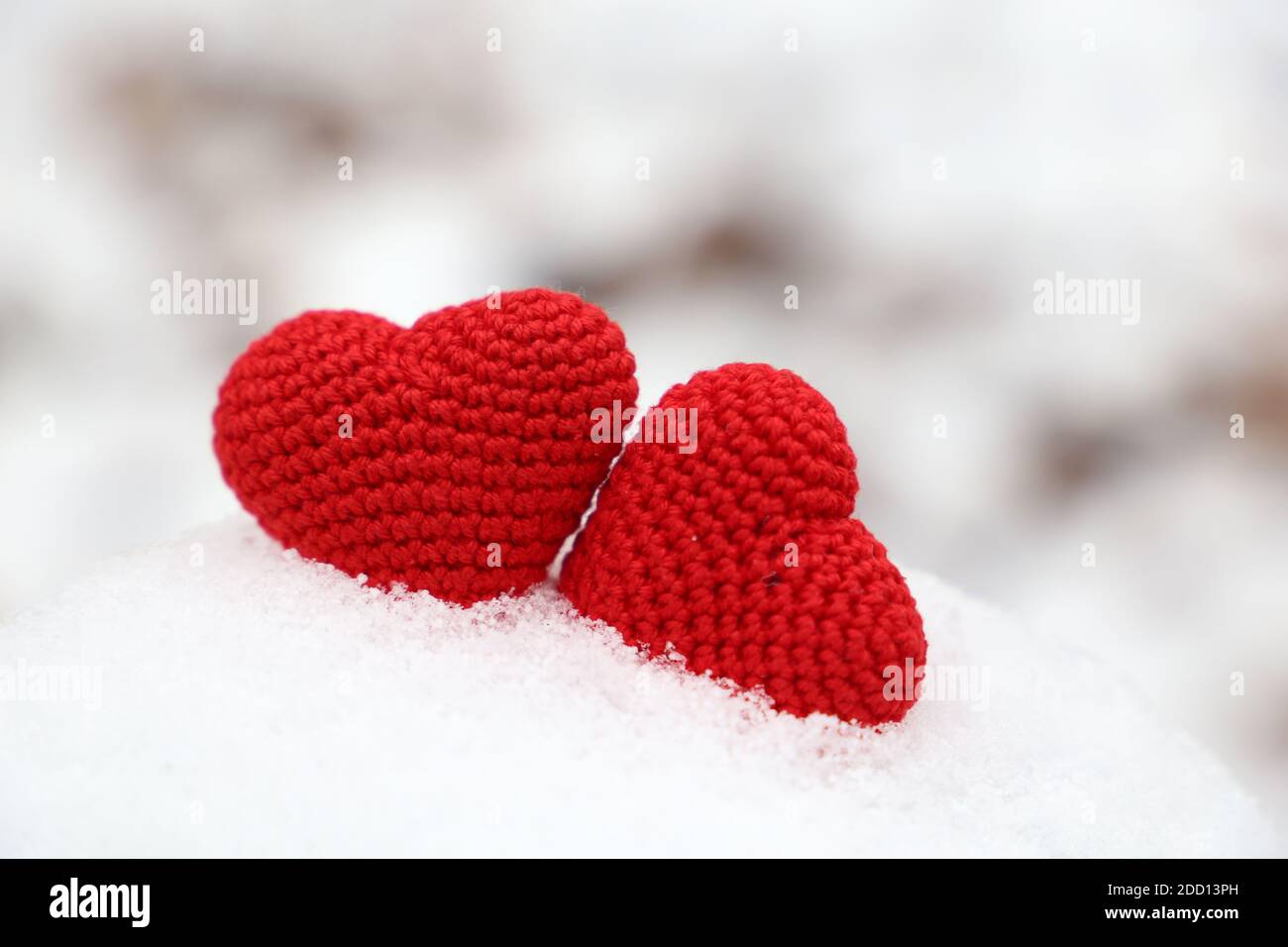 Love hearts, two red knitted symbols of passion in the snow drift. Background for Valentine's card Stock Photo