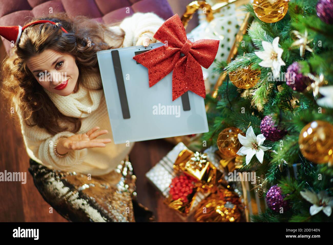 Merry Christmas. Upper view of sad modern woman in gold sequin skirt ...