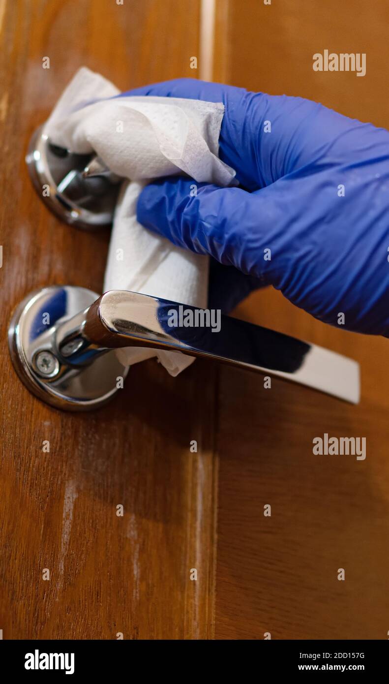 Hand in protective glove with napkin cleaning door handle. Covid19