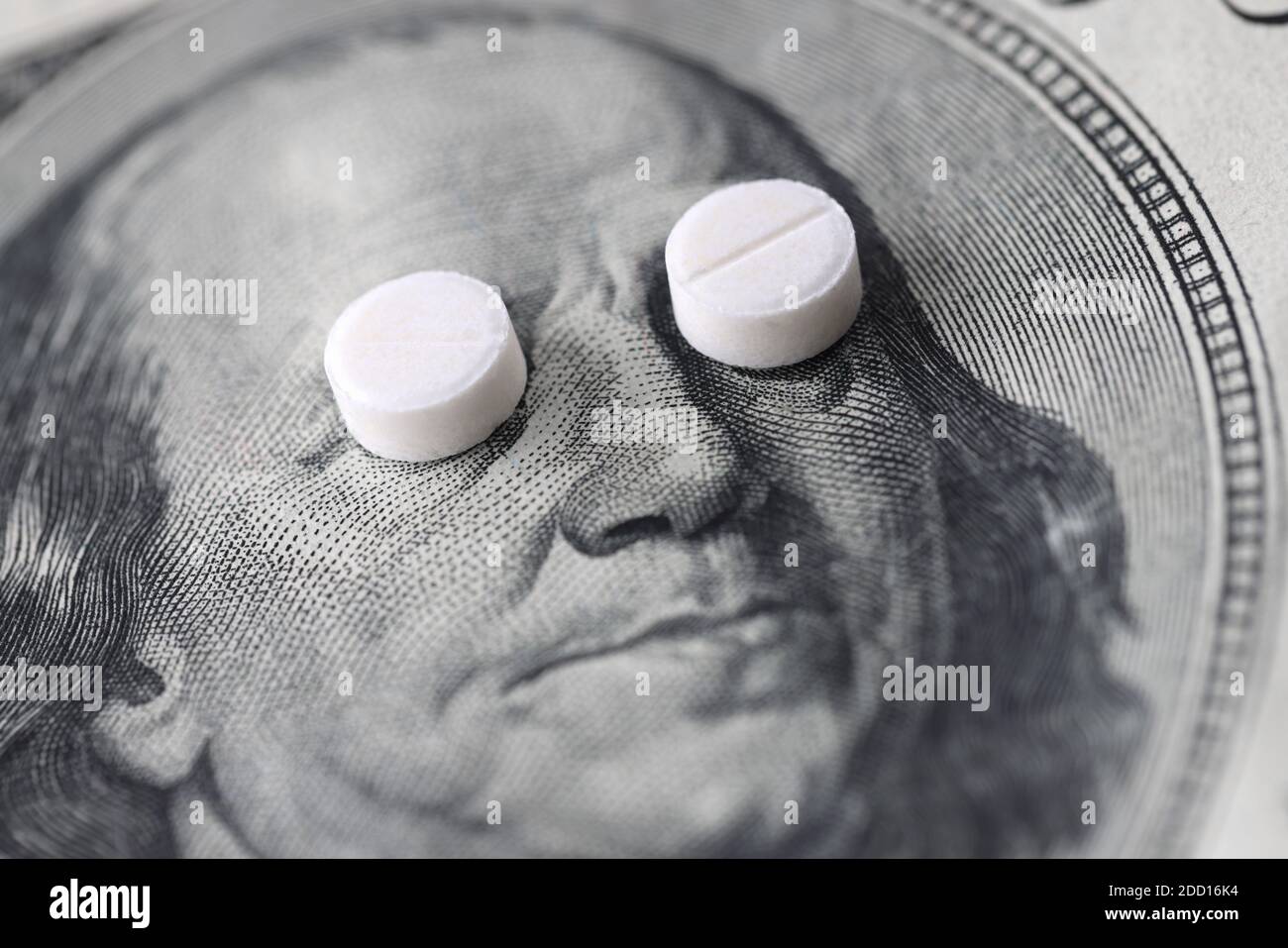 Two small white pills lying on dollar bill close-up Stock Photo