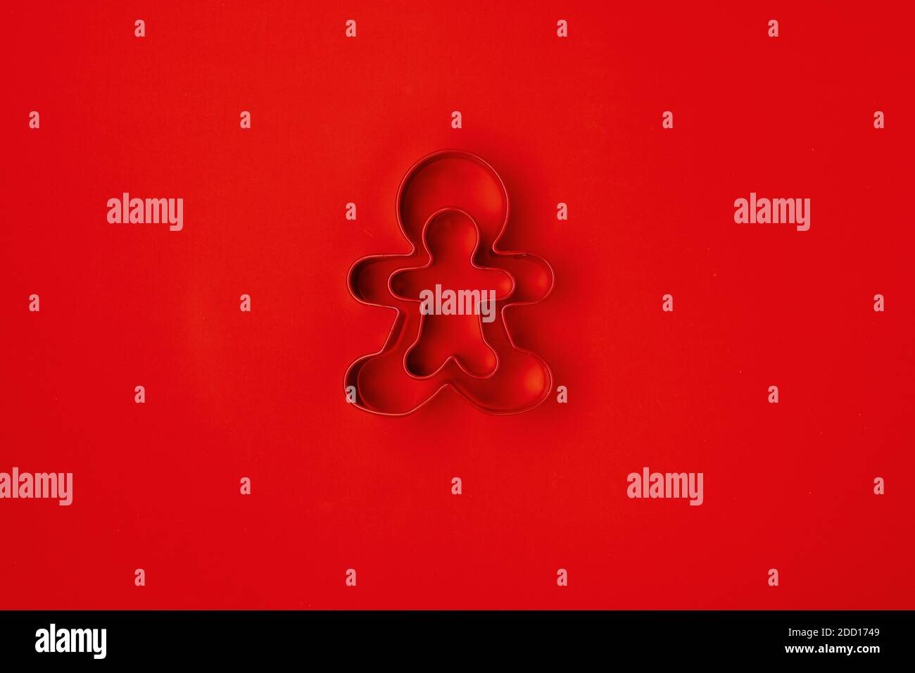 flat lay with gingerbread men cookie cutter on red background. Stock Photo