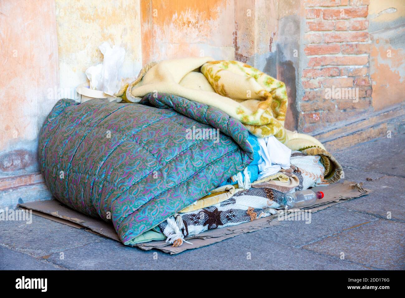 The sleeping place of a homeless man with blankets belongings on the