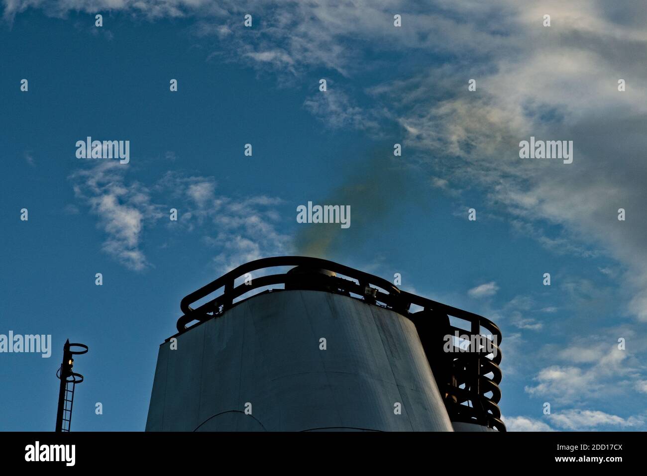 Black smoke coming out of the smokestack of a large ship. Stock Photo