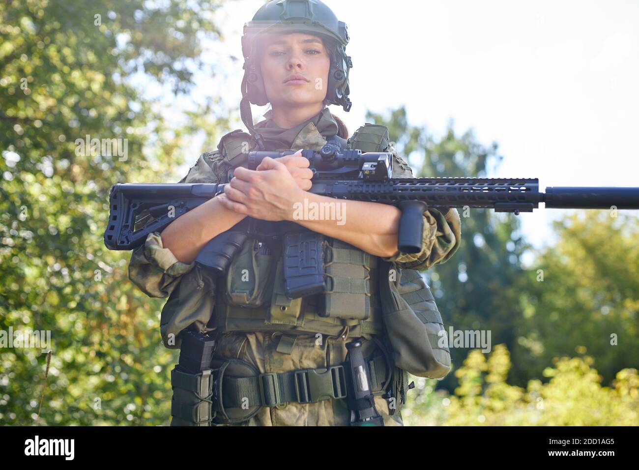 strong brave female army soldier with rifle machine gun standing in the forest, she is ready to shoot at enemy, firearm outdoor shooting range Stock Photo