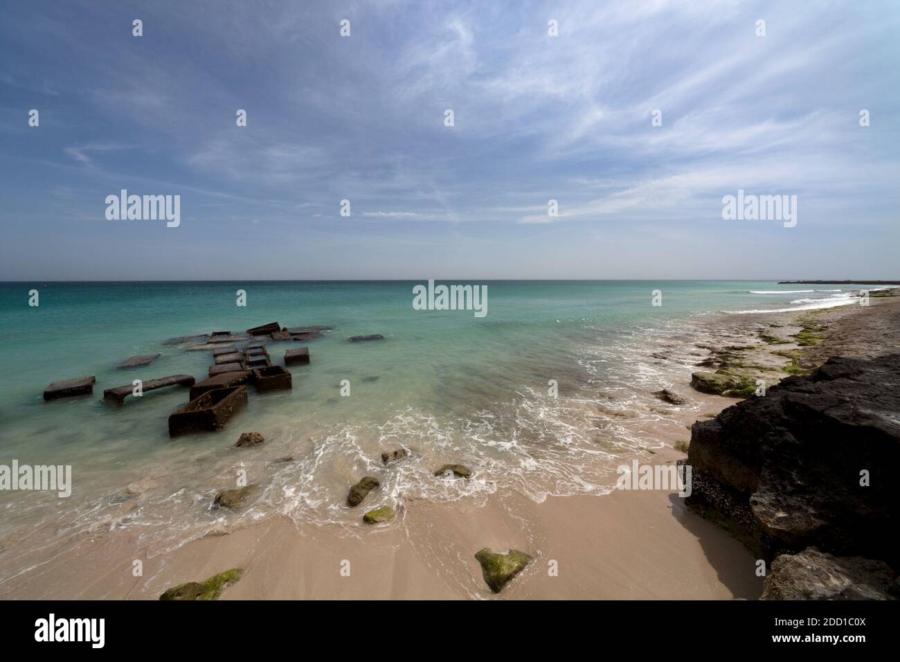 The beach is a bit rocky with cloudy skies Stock Photo - Alamy