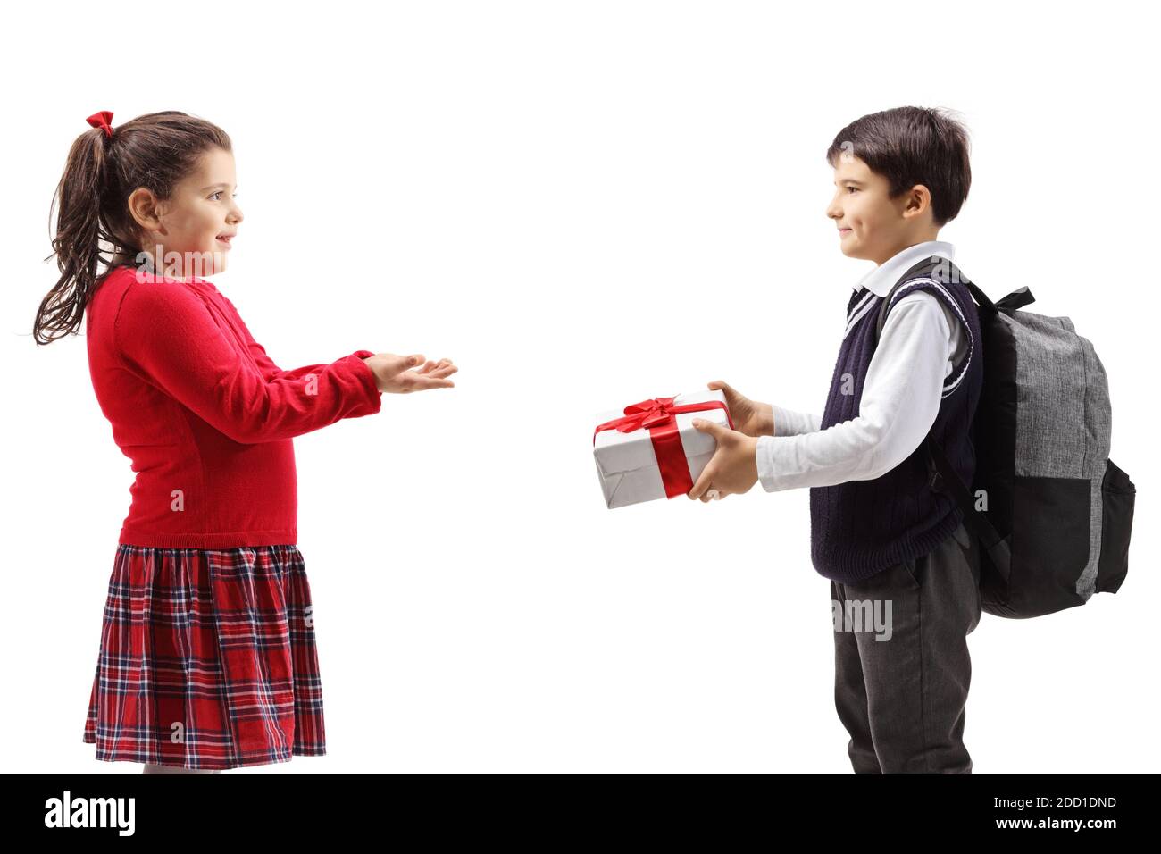 Pupil giving a gift box to a girl in a red dress isolated on white background Stock Photo