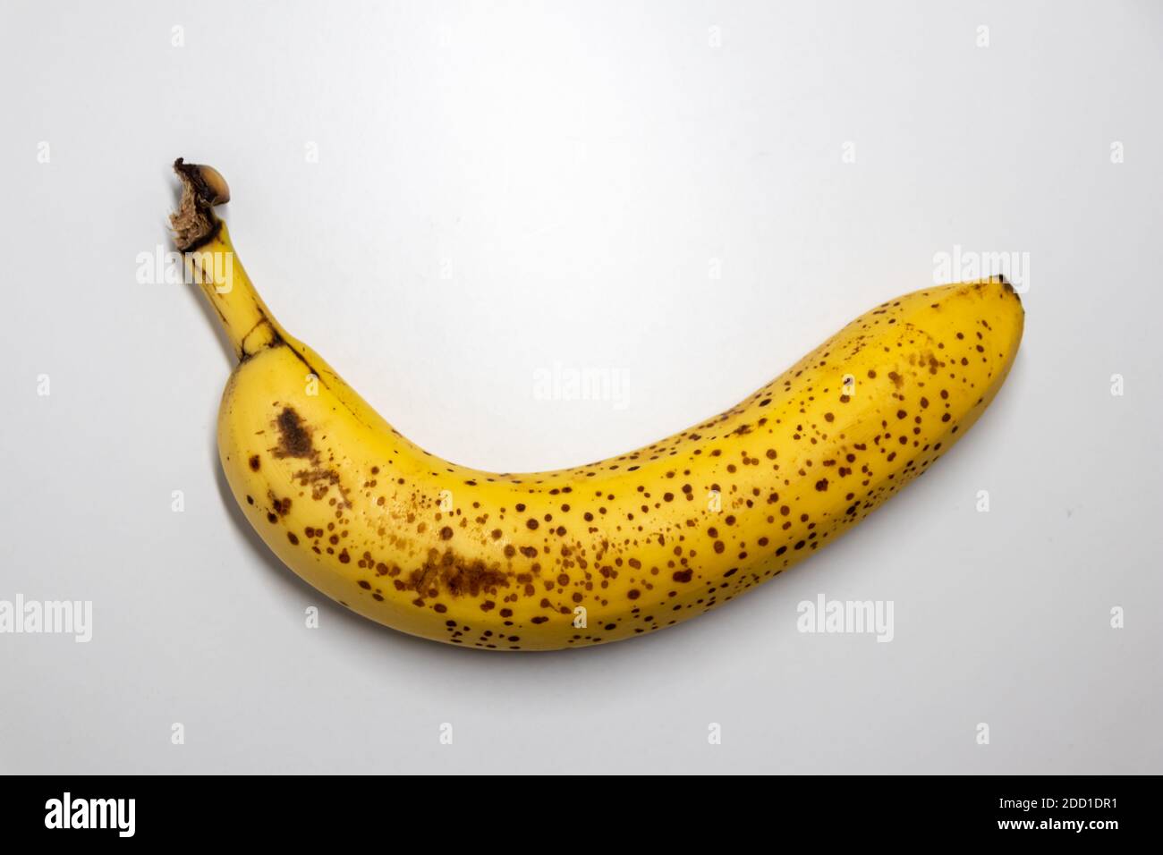 Overripe banana with black dots on white background shows healthy