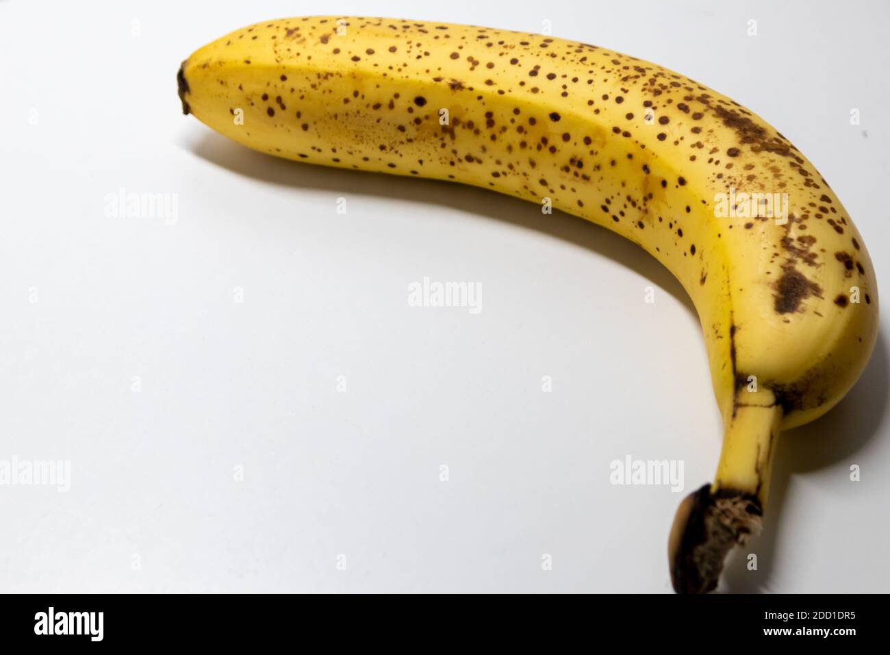 Overripe banana with black dots on white background shows healthy nutrition for vegetarians and vegans with dark spots as studio shot ingredient conta Stock Photo