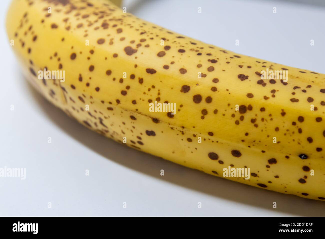 Overripe banana with black dots on white background shows healthy nutrition for vegetarians and vegans with dark spots as studio shot ingredient conta Stock Photo